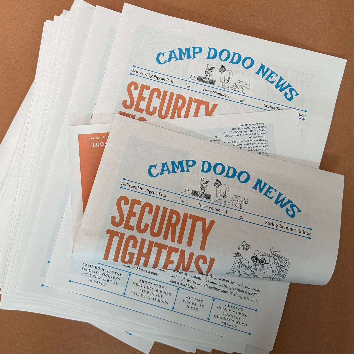 Stack of 'Camp Dodo News' newpapers on a brown background