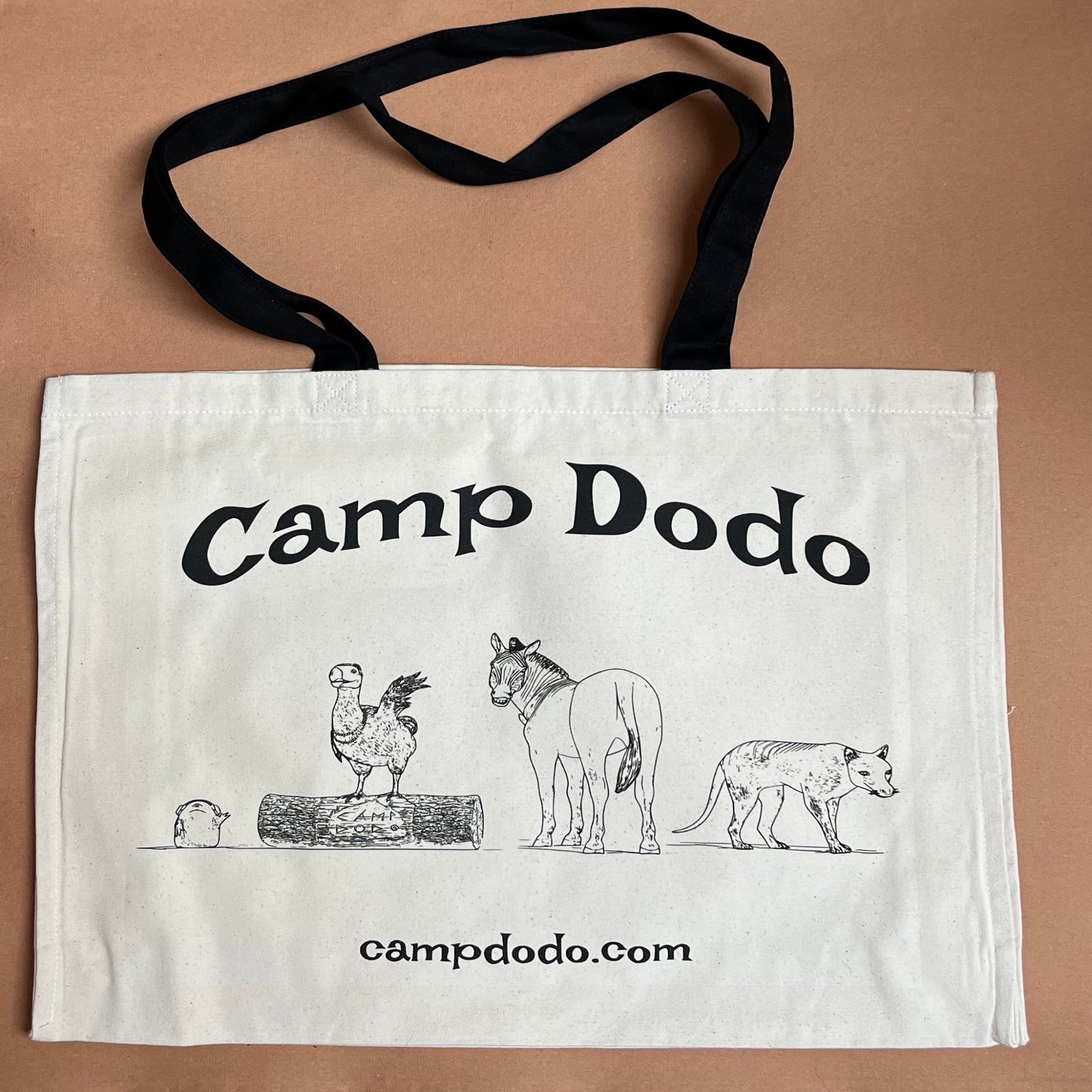 Large, canvas tote bag with 'Camp Dodo' text and illustrations on a beige background