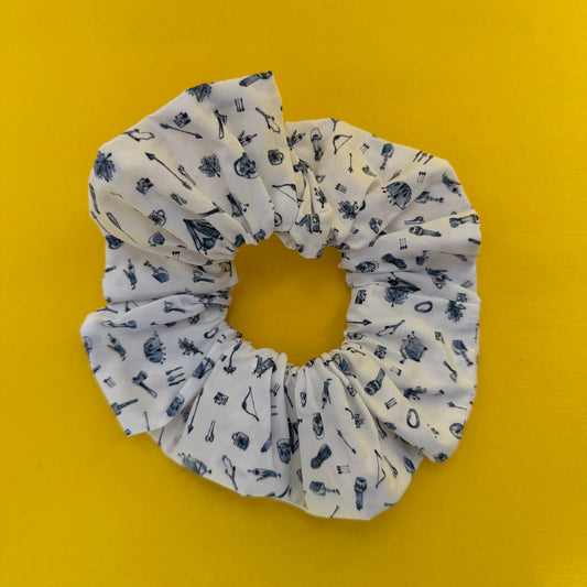 White scrunchie with blue camping icons pattern on a yellow background